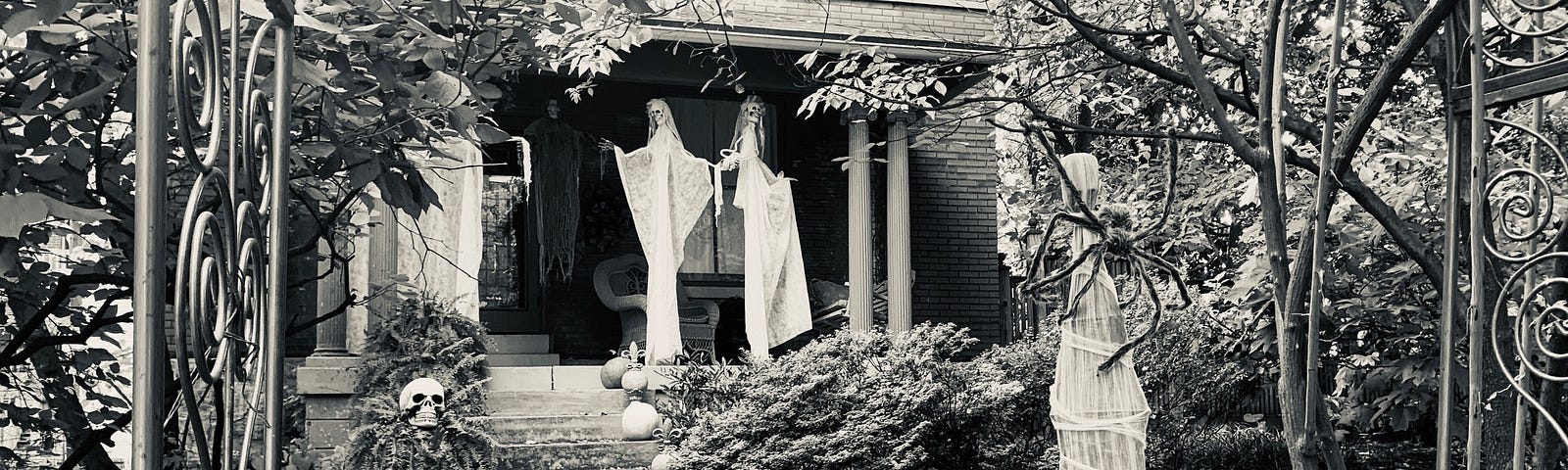 Ghosts and pumpkins on a porch decorated for Halloween.