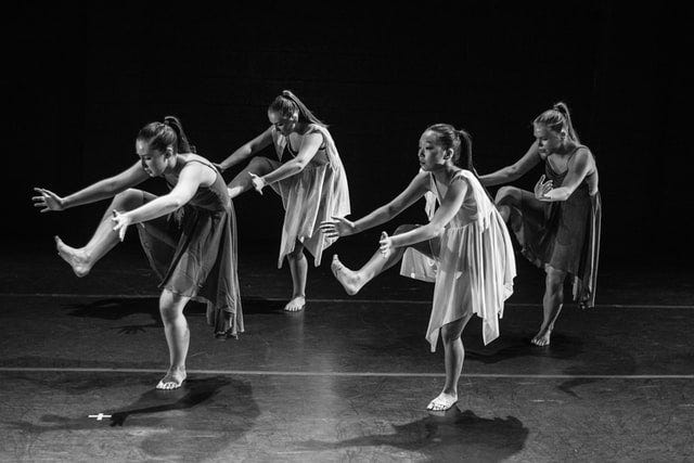 Grayscale photo of dancers performing on stage