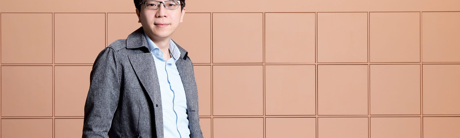 Dr Tommy Lam Tsan-yuk  from the University of Hong Kong stands in front of a nude squared wall.
