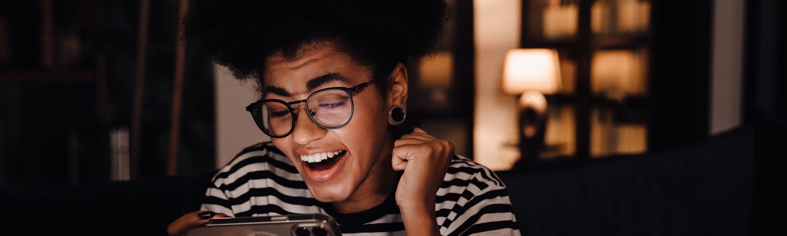 Woman smiling and sitting on couch looking at her mobile phone