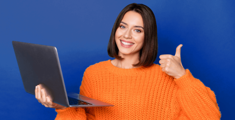 A smiling female designer holding a laptop and giving a thumbs up.