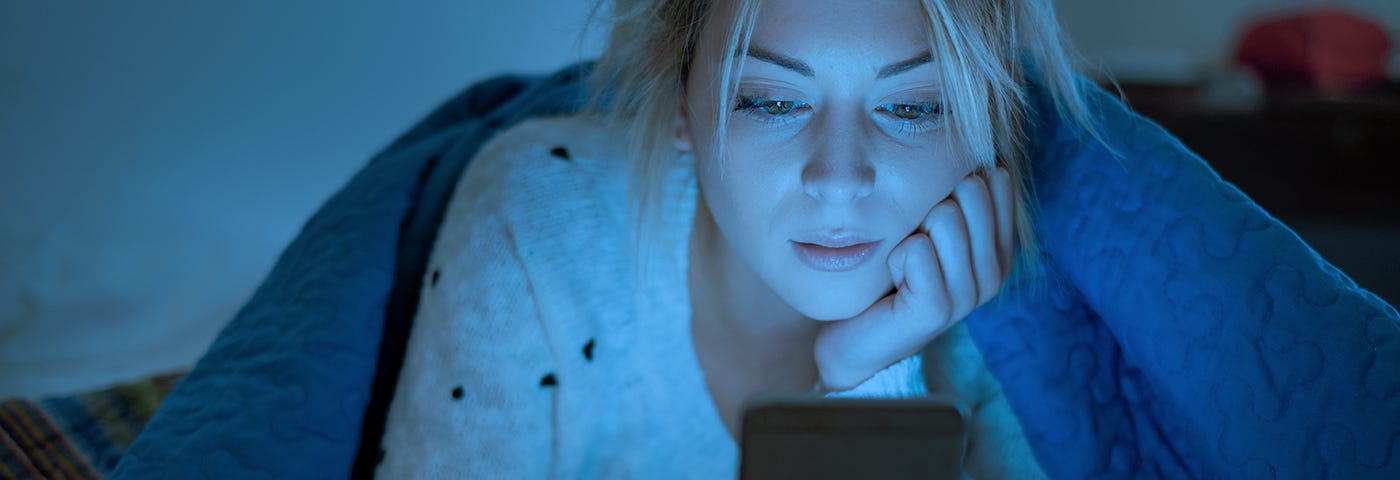 Woman under blanket using a mobile phone