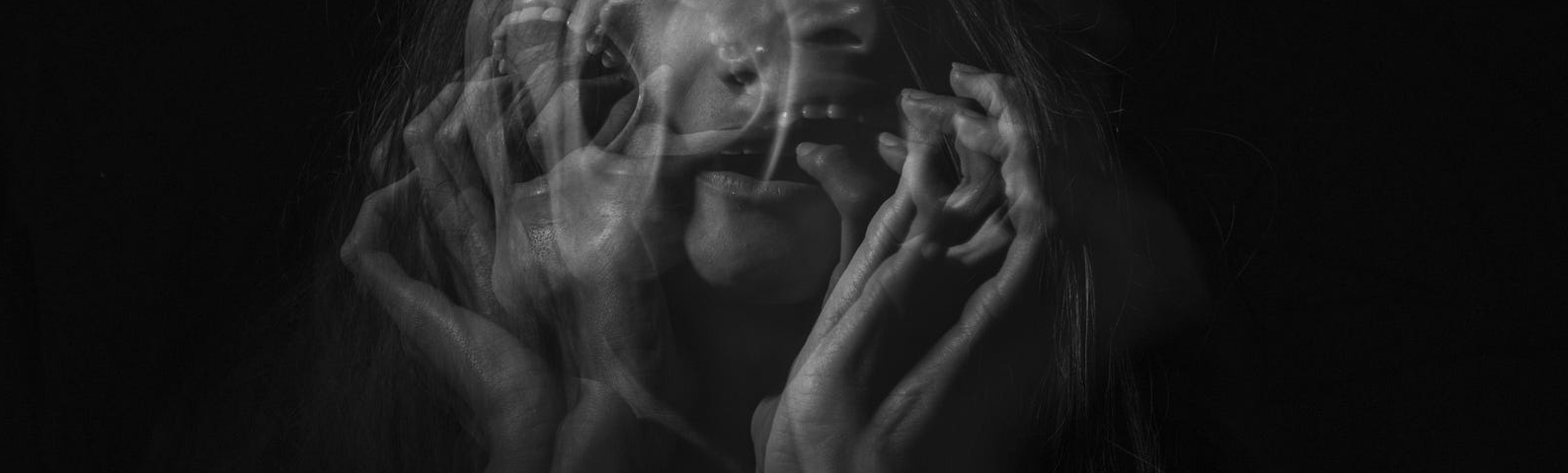 Ghostlike phot of a woman with her hands in front of her face.