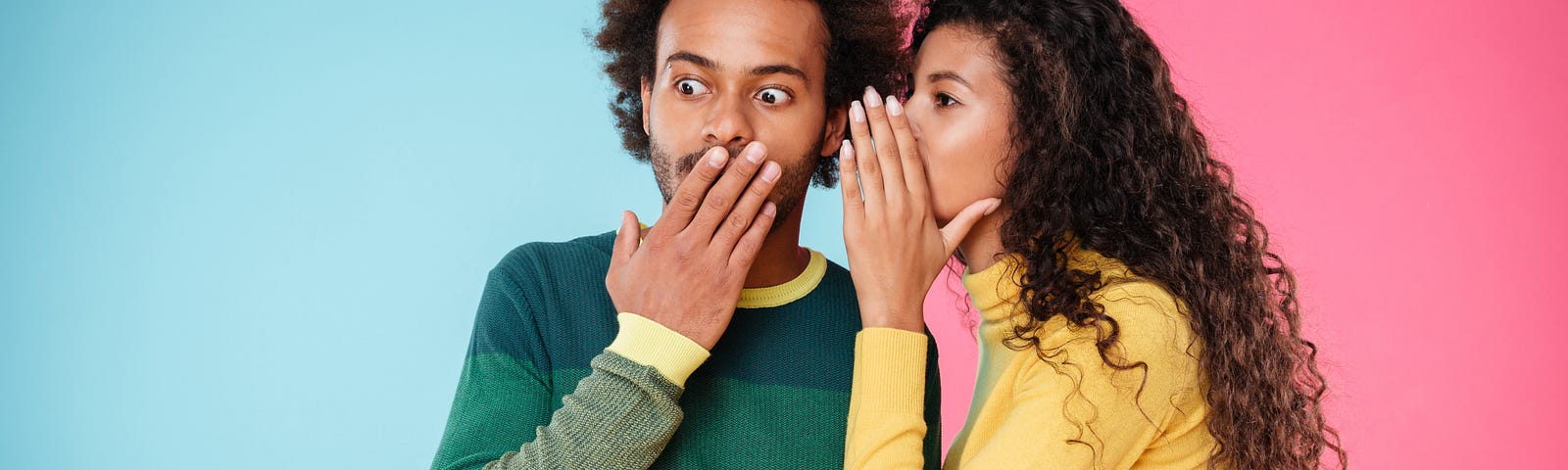 A man and a woman whispering in front of a colorful background of blue and pink.