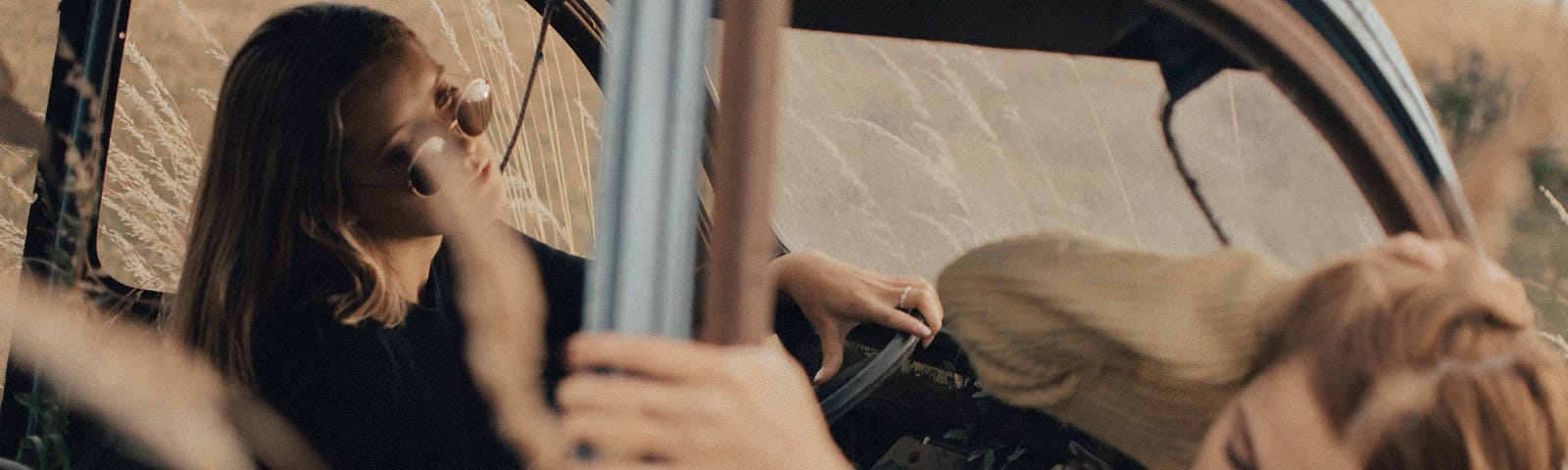 Two girls looking sad in an old car.