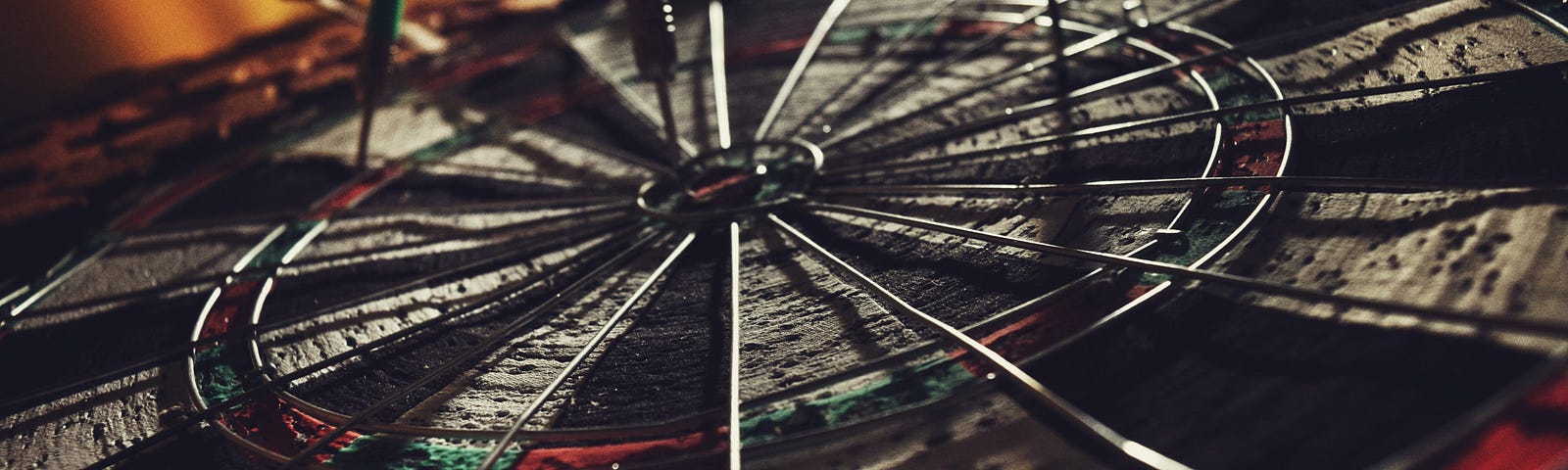 Old used dartboard with three darts in it.