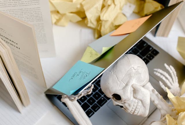 Skeleton figure leaning on a laptop