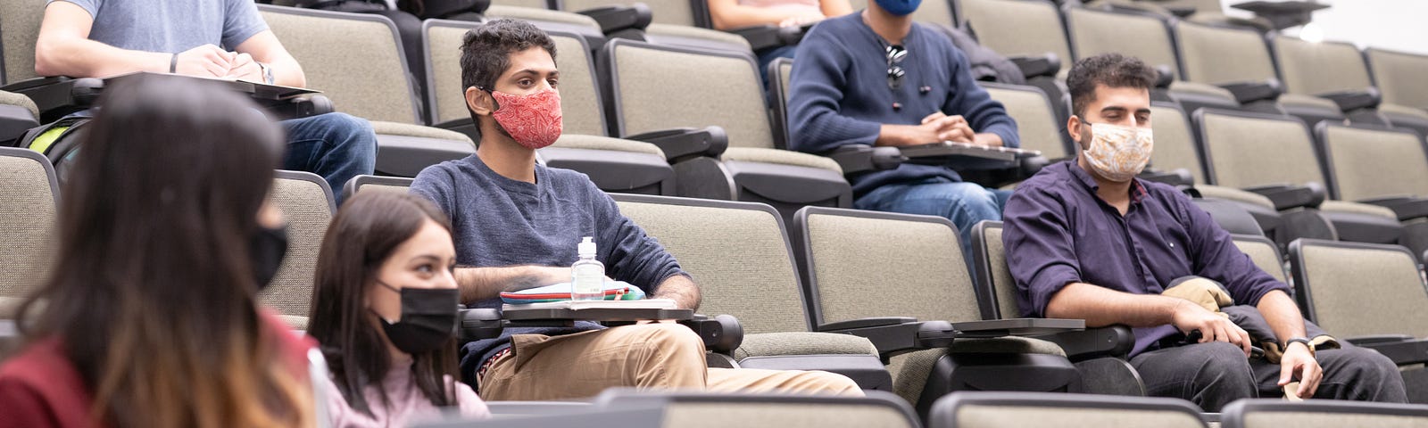 College students wearing face masks in a lecture hall. Photo by FatCamera/Getty Images