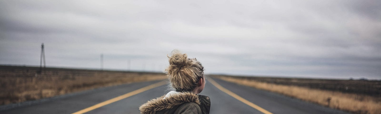 Woman in black jacket standing on free road