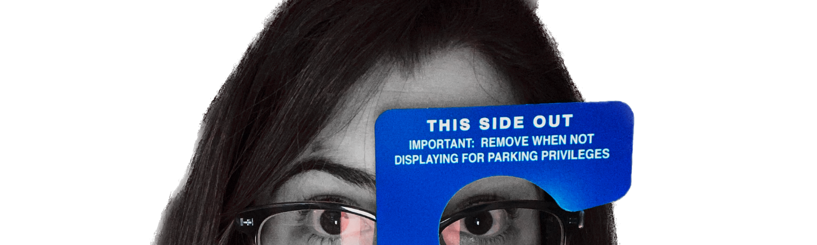 A selfie of the author holding a handicap placard to her face.