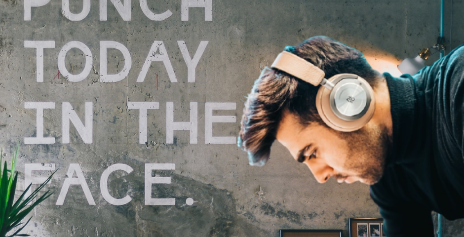 A young man working in an office. On the wall, a sign says: “Punch today in the face” for better productivity.