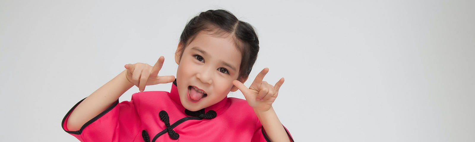 girl wearing pink dress sticking tongue out with hand gestures