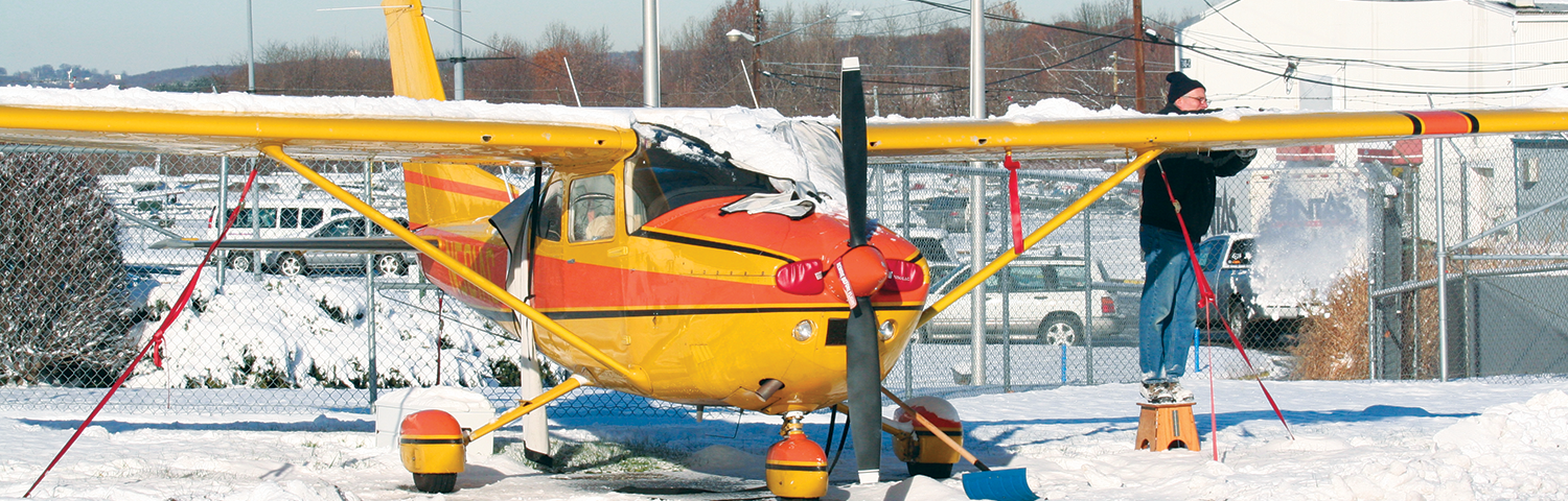 Photo of pilot removing snow from airplane.