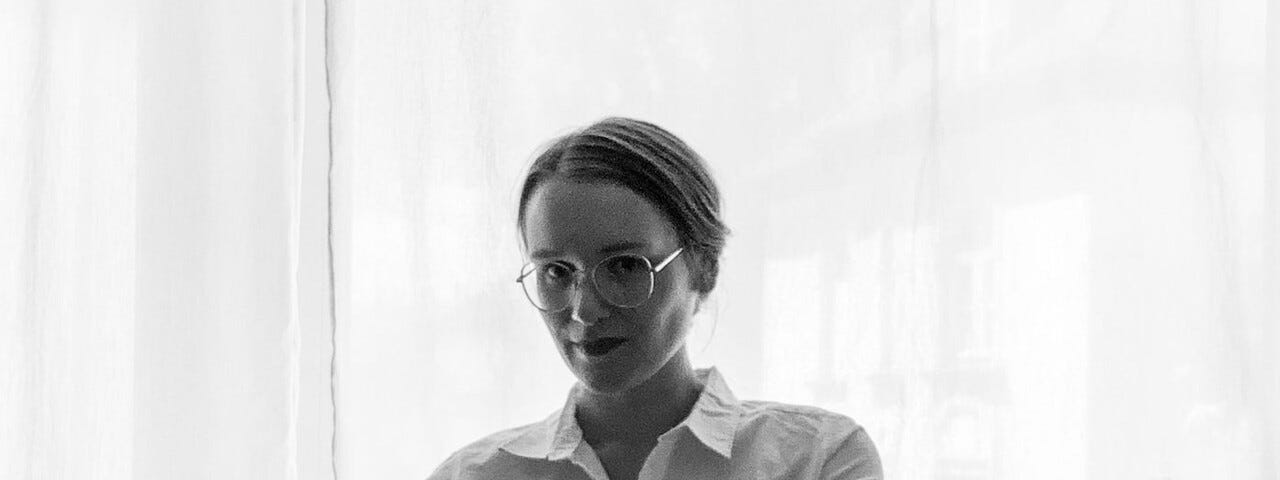 black-white picture of a young woman in a white buisness shirt with arms crossed