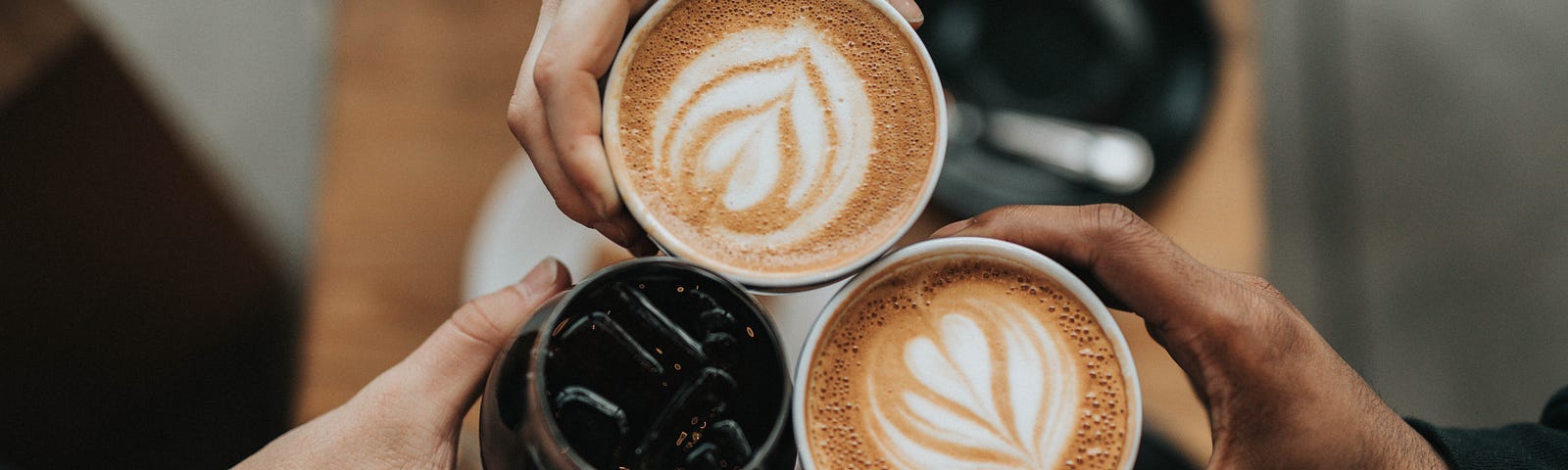 Three people toasting with three cups of coffee