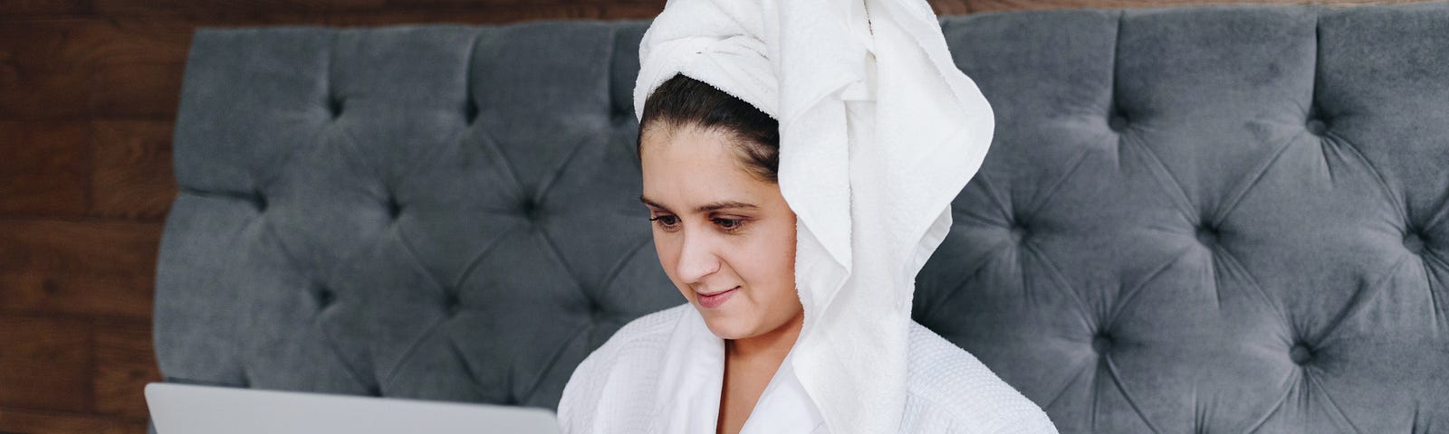 A woman working on her bed right after she has had a shower.