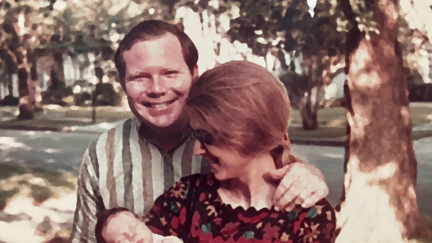 A modified photo of my parents — a man stands behind a woman. He is beaming. She is gazing at a baby in her arms.