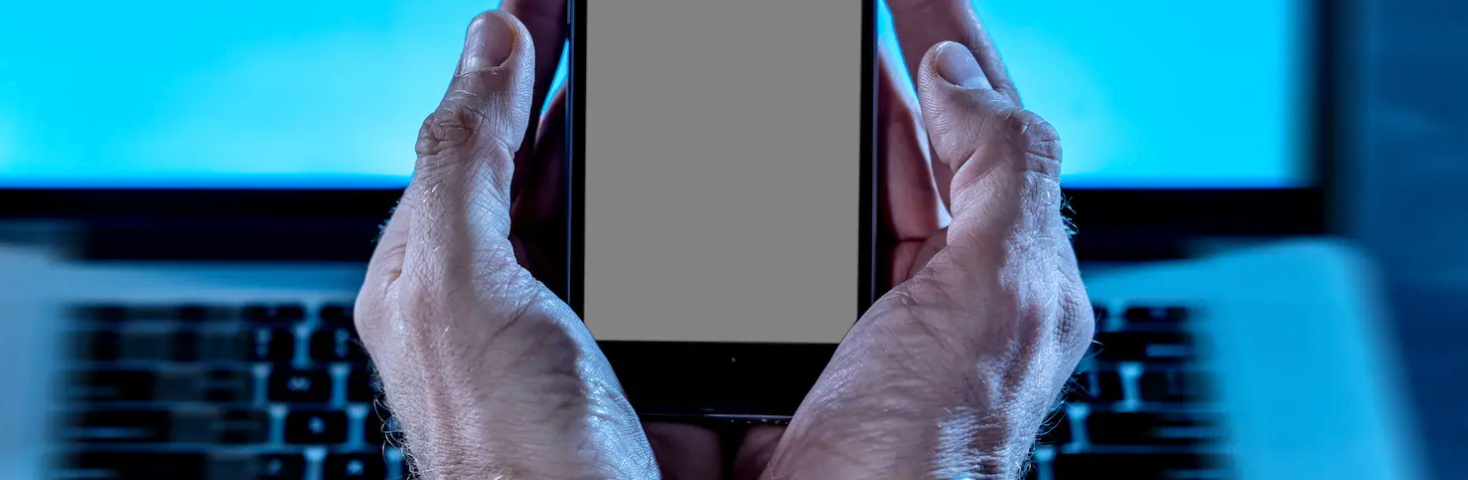 Photograph of man’s hands chained around a smartphone.