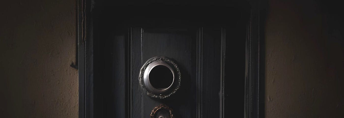 A dark and scary door with a peephole.