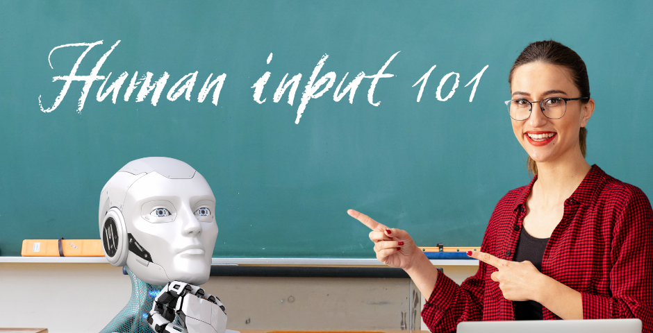 An AI robot sits in a classroom while a female teacher points to a chalkboard.