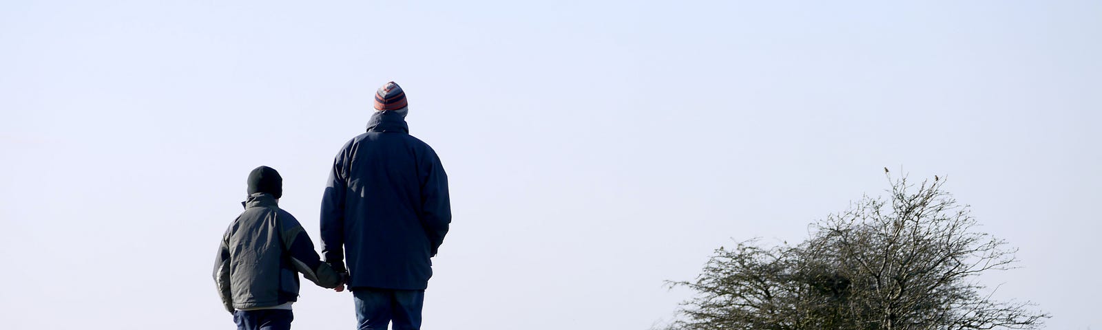 Dad and son walking towards the ocean.