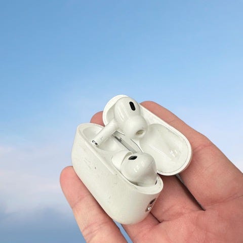 A hand holding out a pair of AirPod Pros 2