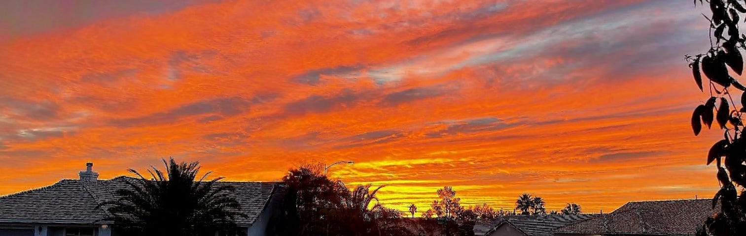 Colorful sunrise with a residential neighborhood in the foreground.