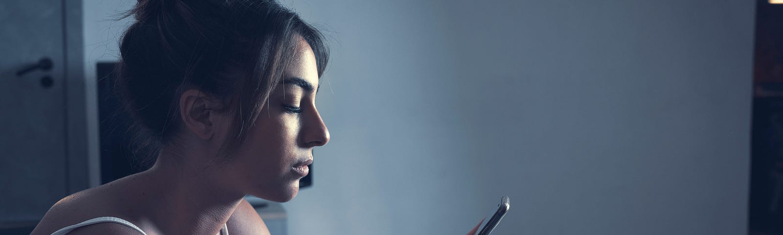 A woman holding a cell phone sexting with someone while looking depressed