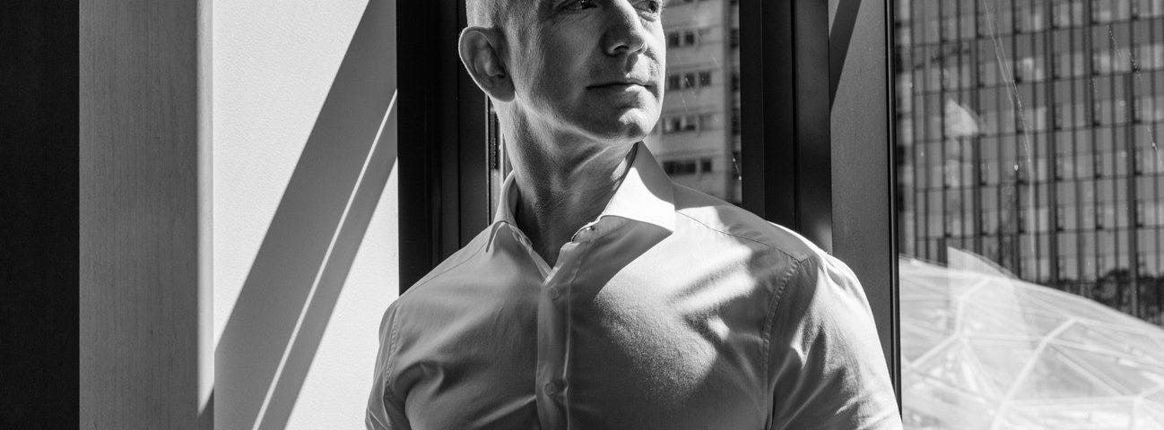 Jeff Bezos standing beside a window.