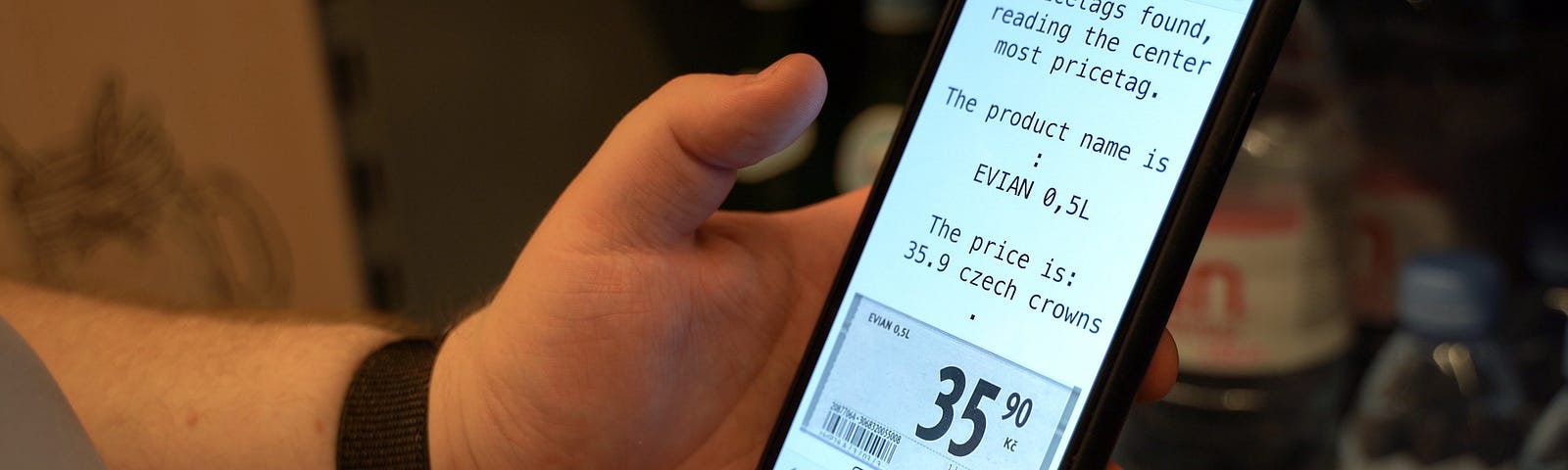 A hand holidng a mobile phone showing a screen with text extracted from a pricetag and a picture of the pricetag below the text.