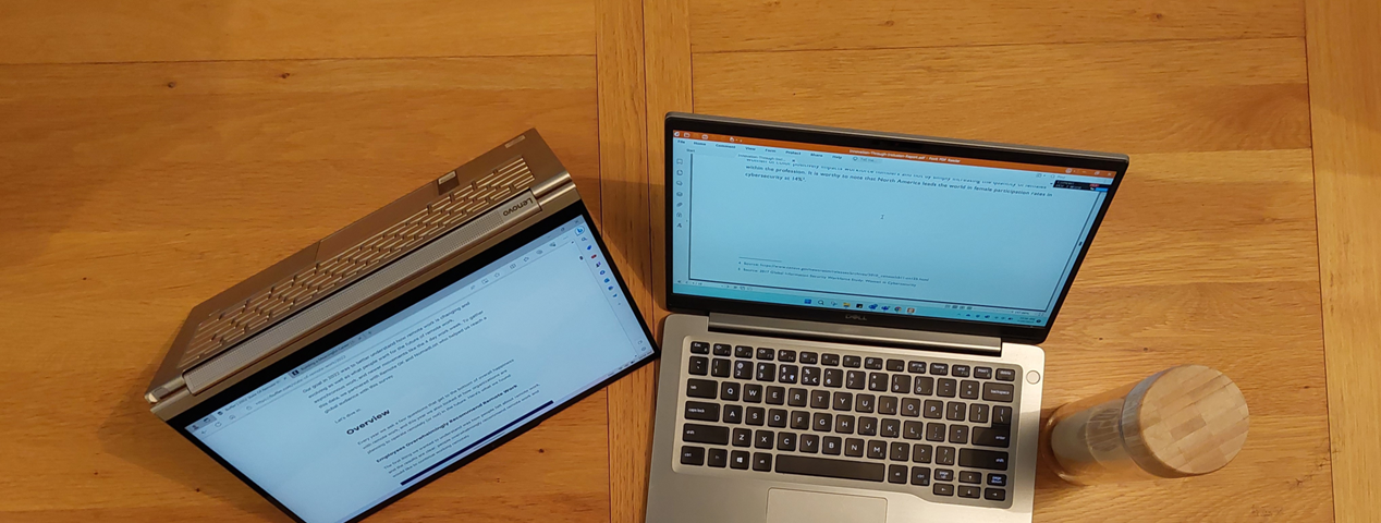 2 laptop computers (1 in tablet mode), a phone, and a coffee mug/bottle on a brown table