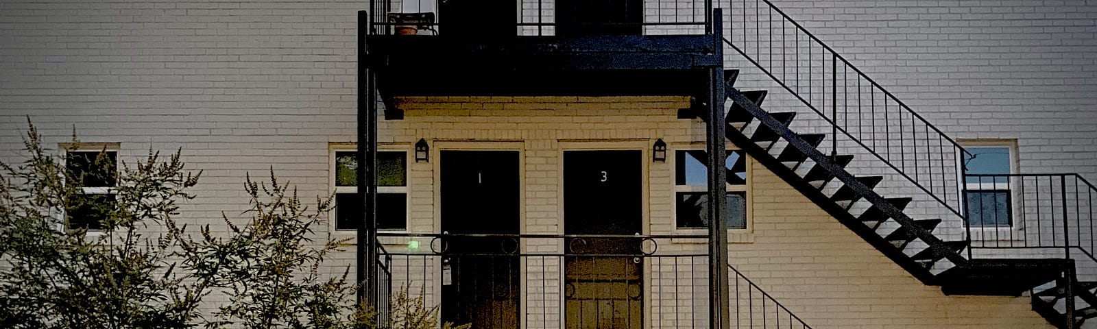 a picture of an apartment building outside- you can see the staircases and mulitple doors