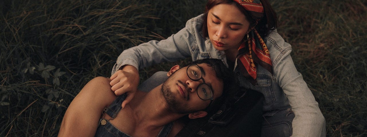 a man and a woman lay together in the grass