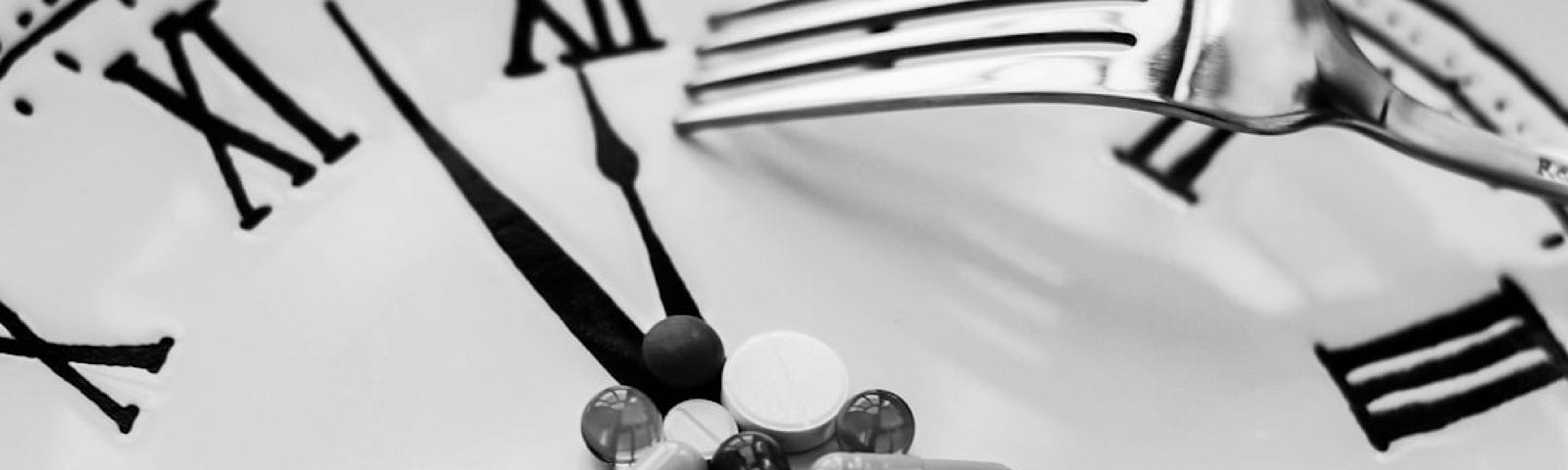 A clock with a pile of pills on it and a downturned fork resting next to them. The clock may be a plate with a clock face on it.