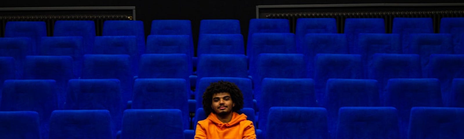 Marius GIRE took this photo of a man in an orange hoodie sitting alone in an empty movie theater.