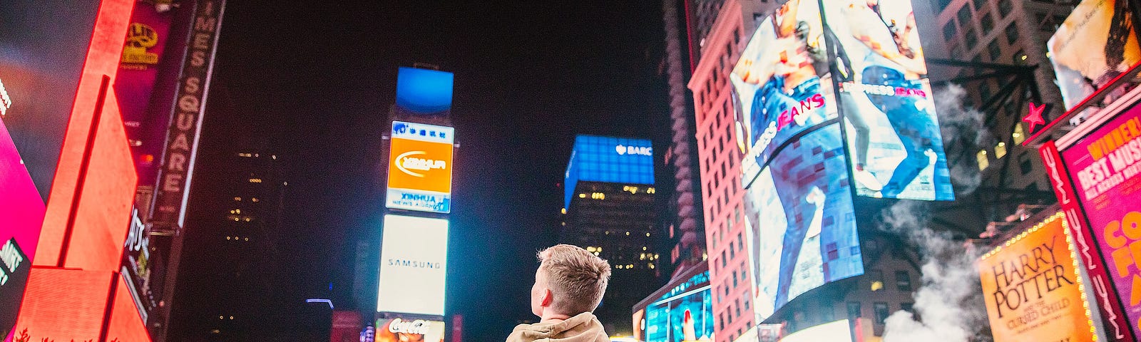 Image of a person in a white hoodie standing in front of Time Square in New York City