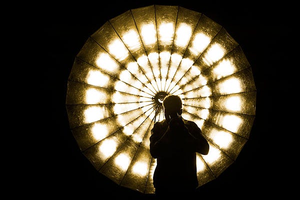 A shadowed figure stands in front of a large, circular light