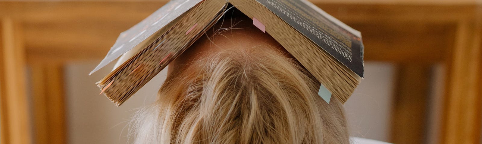 girl with her head tipped back and a book covering her face