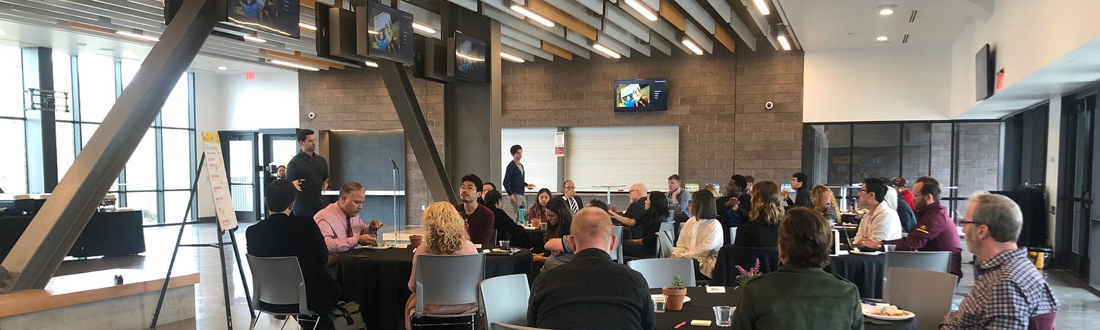 Researchers are seated at multiple tables as they listen to a presentation.