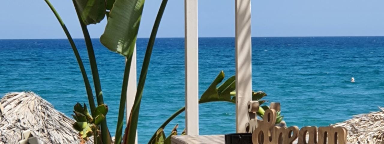 Furniture set by the sea with the wooden word “dream” placed on a table.