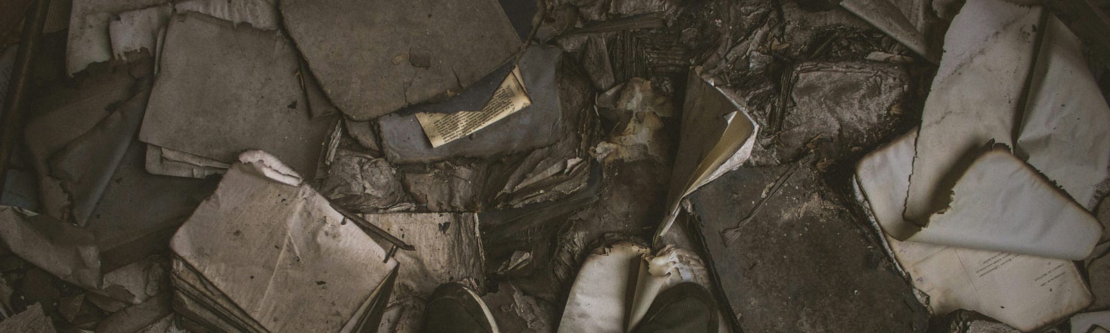 Someone standing over a piles of burnt books and personal things.