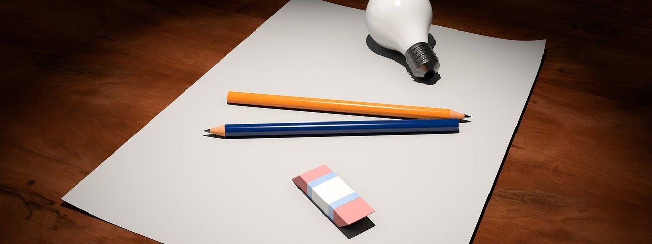 A sheet of paper with pencils, rubber and light bulb sitting on it.