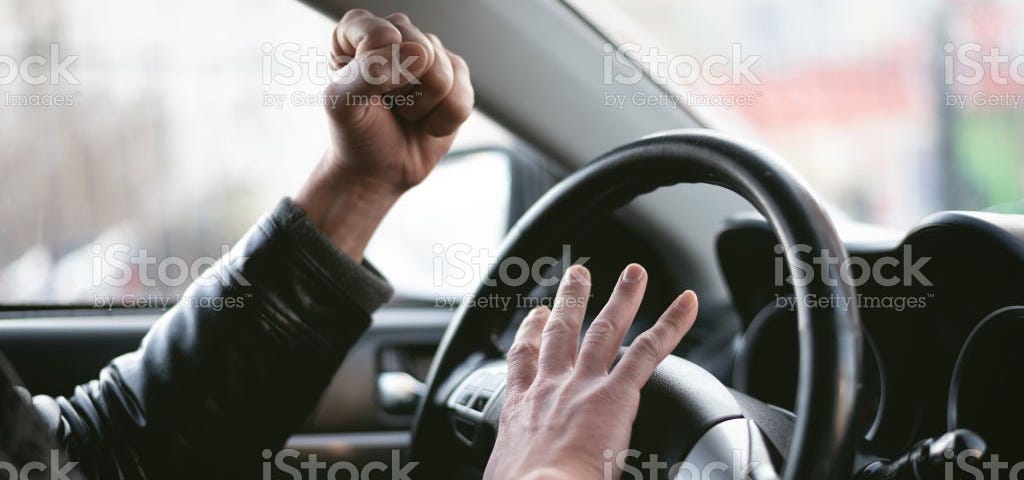 person behind the wheel of car, honking and fist up in anger