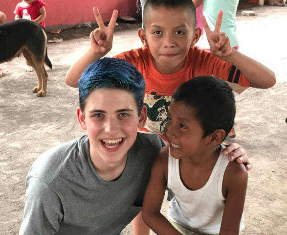 young American boy poses for a picture with two younger Guatemalan boys