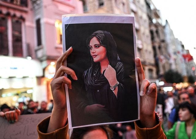 A protestor in Iran holding the image of Mahsa Amini, who was ‘killed’ by the state. Credits: Harper’s Bazaar