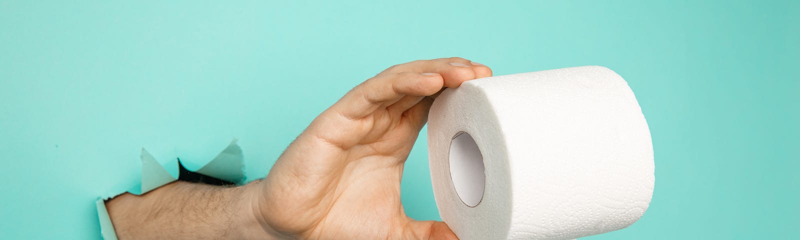 man-s-hand-holding-roll-toilet-paper-from-blue-torn-background — Un Swede