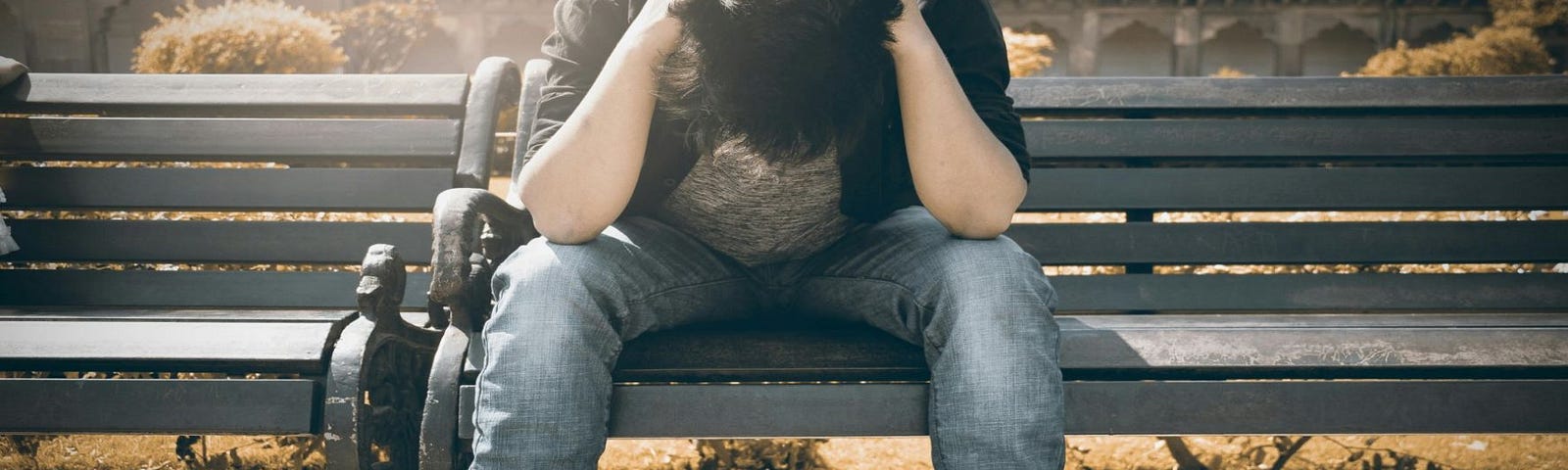 A stressed and troubled man sitting on a bench.