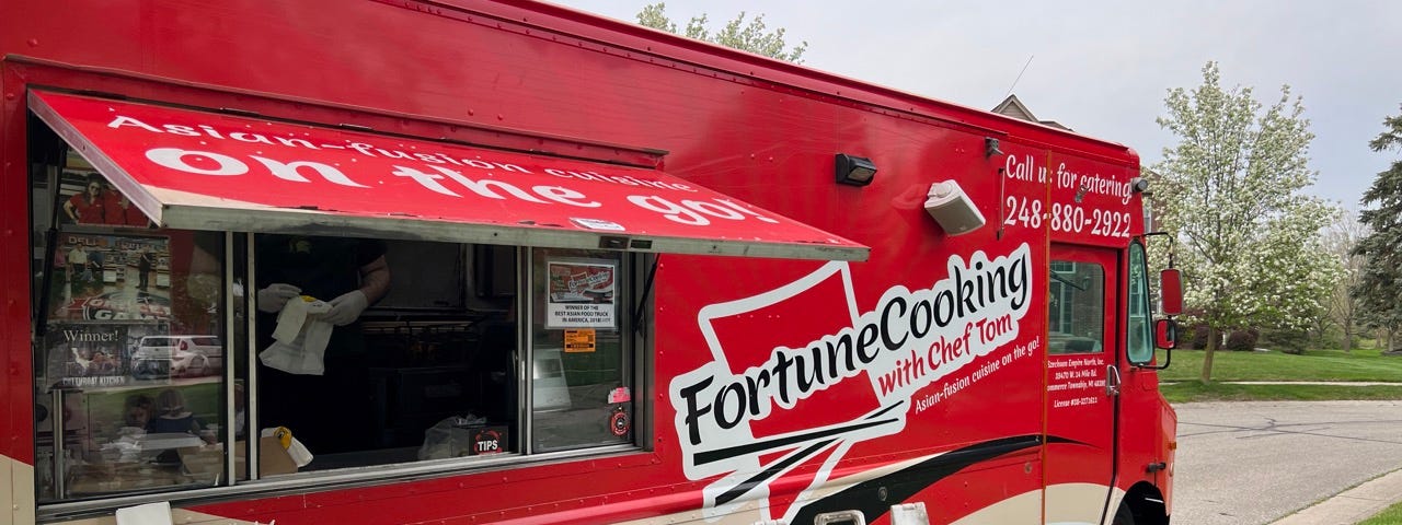 A large red food truck called Fortune Cooking specializing in serving Asian food.