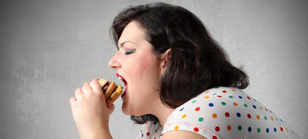 Very large woman eating a hamburger