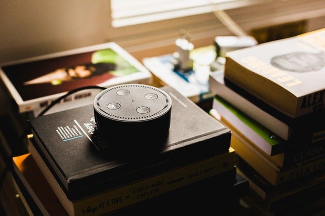 Amazon smart speaker with voice technology sits on books and publications.